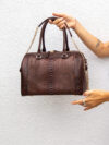 woman holding leather brown bag on white wall back 2025 02 22 11 11 00 utc